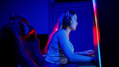 Seksi dövmeli genç kadın neon oyun kulübünde oturuyor ve oyun oynuyor.