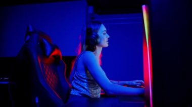 Neon oyun kulübünde oturan dövmeli genç bir kadın oyun oynuyor ve hayal kırıklığına uğruyor.