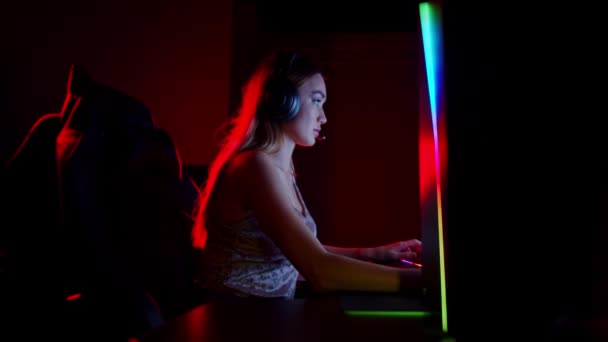 Jeune femme tatouée assise dans un club de jeu au néon gagne le jeu en se tournant vers la caméra et en montrant un pouce vers le haut — Video