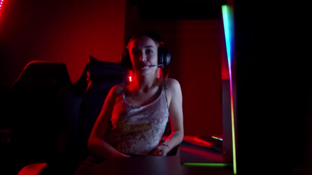 Getatoeëerde jonge vrouw zitten in neon gaming club en zwaaien met haar hand - kijken in de camera — Stockvideo