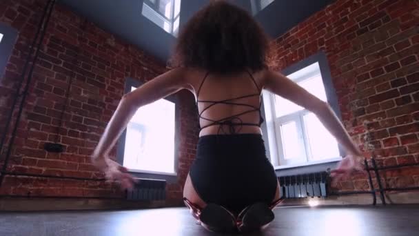 Mladá žena s kudrnatými vlasy tančí v podkrovním studiu s oranžovými cihlovými stěnami — Stock video