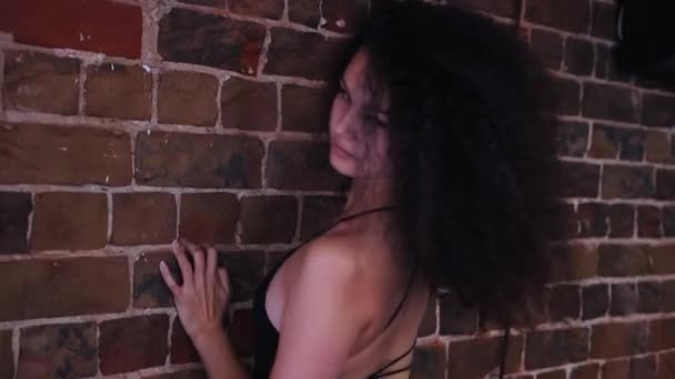 Młoda, atrakcyjna uśmiechnięta kobieta z kręconymi włosami tańcząca przy murze — Wideo stockowe