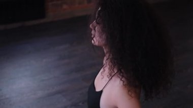 Genç, şehvetli, kıvırcık saçlı, yerde dans eden seksi kadın dansçı.
