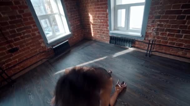 어두운 바닥에서 젊은 여자가 하이힐을 신고 섹시 한 춤을 추며 바닥에서 춤을 추고 있는 스튜디오 안 의 스트립 댄스 — 비디오