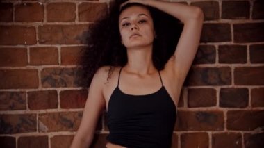 Stüdyoda striptiz dansı - Turuncu tuğla duvarda dans eden genç ve çekici kıvırcık kadın