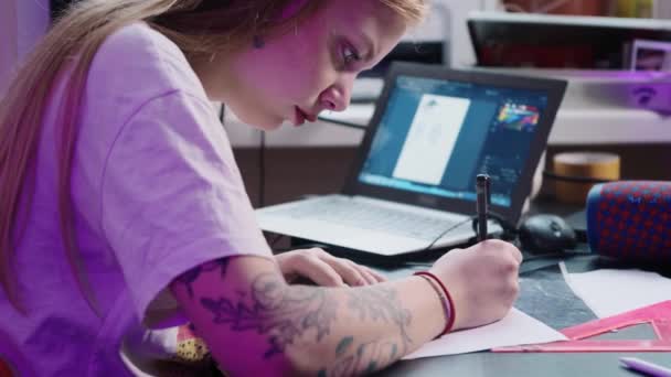 Ung kvinna tatuering artist ritar skiss för tatuering i studio framför laptop — Stockvideo