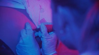 Dövme seansı - Dövme ustası mavi ışıklı turuncu haç dövmesi yapıyor - kaburgalarda dövme