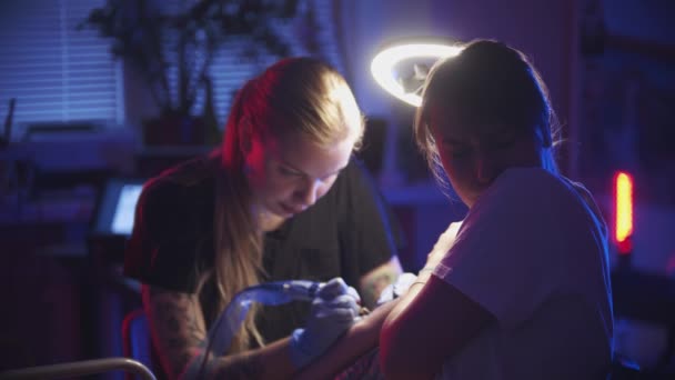 Sessão de tatuagem - jovem mulher recebendo uma tatuagem minimalista em seu braço - sentindo dor — Vídeo de Stock
