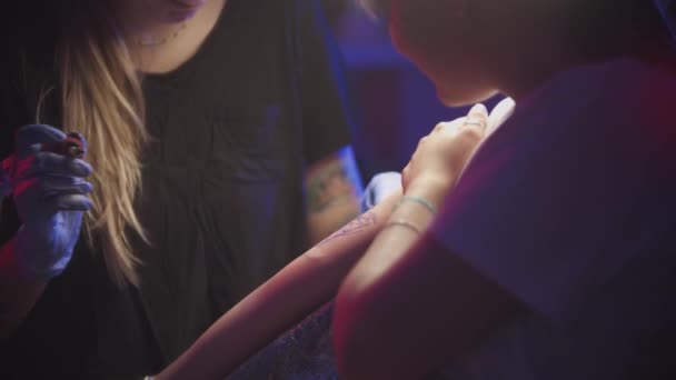 Sesja tatuażowa - młoda kobieta robi sobie tatuaż na ramieniu przez mistrza — Wideo stockowe