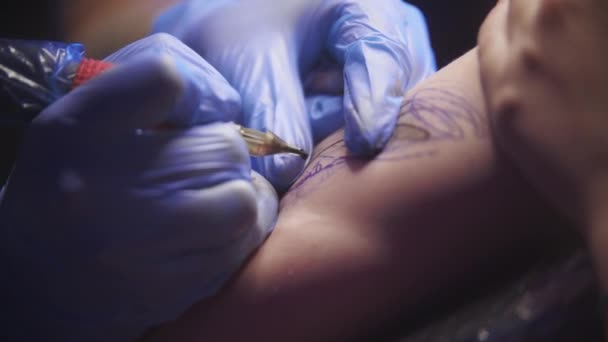Sesja tatuażowa - młoda kobieta robi sobie czarny tatuaż na ramieniu — Wideo stockowe