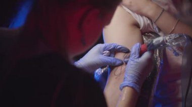 Dövme oturumu - kadının koluna soyut bir yüz dövmesi yaptırması - mavi renk eklemesi