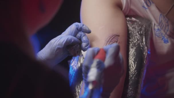 Sessione di tatuaggio - donna che si fa un tatuaggio facciale astratto nero e rosso — Video Stock