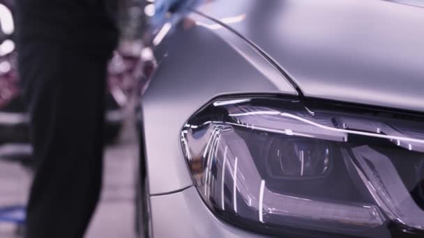 Авто-деталізація - людина працівник полірує поверхні сірого автомобіля — стокове відео