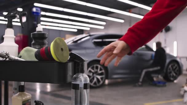 Авто деталізований салон - працівник, який полірує поверхні автомобіля - інший чоловік бере розпилювач для очищення з переднього плану — стокове відео