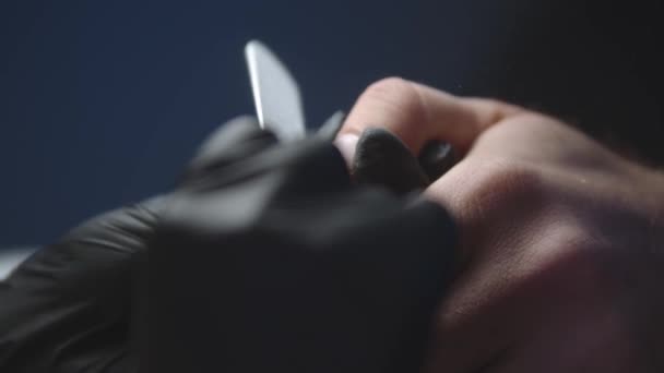 Manicurista con guantes negros haciendo uñas de hombre con un tablero de esmeril suave - aserrando el borde libre de uñas — Vídeo de stock