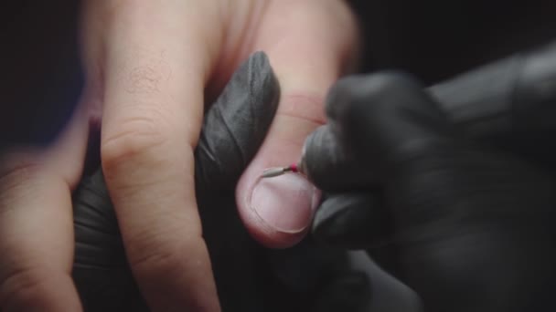 Маникюрша делает маникюр на грубых мужских руках с помощью небольшого бурового устройства с острым кончиком — стоковое видео