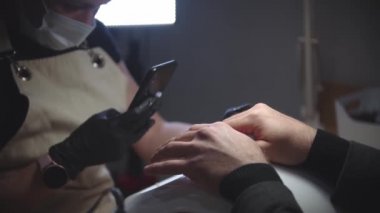 Erkek manikürü - bir kadın müşterisinin elinin fotoğrafını çeker