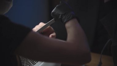 Erkek manikür seansı - siyah eldivenlerin ustası tırnak törpüsüyle tırnak testeresi