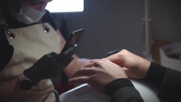 Мужской маникюр - женщина фотографирует руку своего клиента — стоковое видео