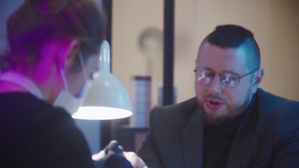Чоловічий манікюр - бізнесмен в сірому костюмі, що сидить на манікюрній сесії і розмовляє з майстром — стокове відео