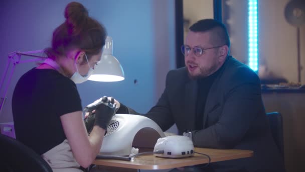 Mężczyzna manicure - biznesmen w szarym stroju siedzi na manicure sesji i rozmowy z mistrzem paznokci — Wideo stockowe
