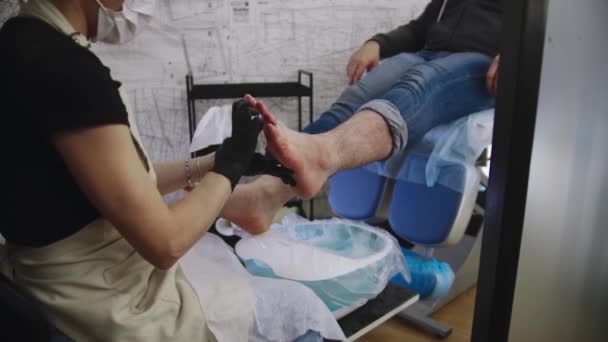 Διαδικασία πεντικιούρ - ο κύριος σκουπίζει τα πόδια του αρσενικού πελάτη της μετά από ένα λουτρό αλατιού — Αρχείο Βίντεο