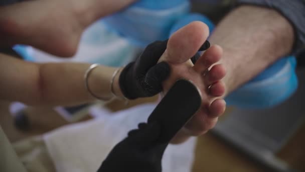 Διαδικασία πεντικιούρ - ο κύριος γυαλίζει το σκληρό δέρμα του πελάτη της μετά από ένα λουτρό αλατιού χρησιμοποιώντας ένα σμύριδα — Αρχείο Βίντεο