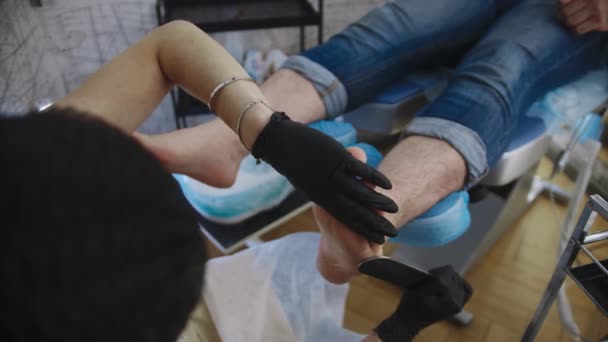 Pedicure procedure - the master polishes the harsh skin of her male client after a salt bath using an emery board — Stock Video