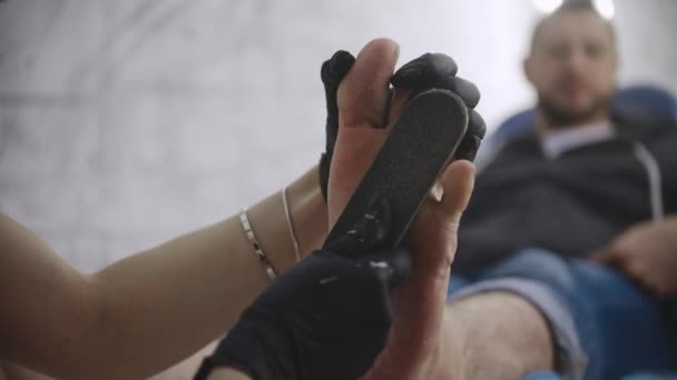 Procedimento de pedicure - o mestre polir a pele dura nos pés de seu cliente masculino — Vídeo de Stock