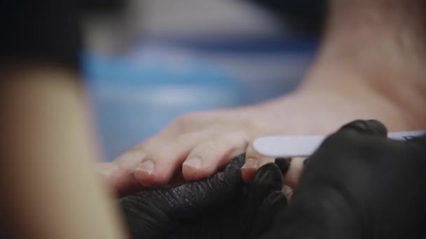Procedura pedicure - mistrz piłuje paznokcie u nóg swojego męskiego klienta — Wideo stockowe