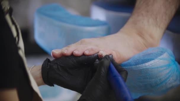 Pedicure procedure - the master grinding the toenails of her male client — Stock Video