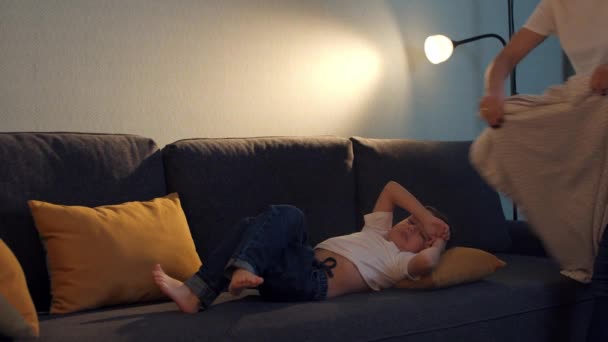 Счастливая семья - маленький мальчик засыпает на диване и мать покрывает его одеялом — стоковое видео
