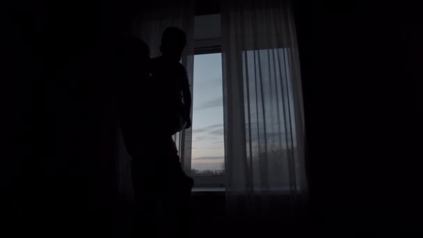 Mor håller sin son och öppnar gardinerna — Stockvideo