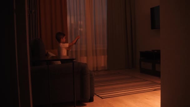 Un niño apaga la televisión y corre de la sala de estar a la cocina a su madre — Vídeos de Stock