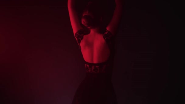 Jeune belle femme ballerine en robe noire dansant gracieusement lentement dans l'éclairage rouge — Video