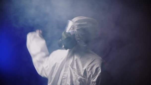 Una mujer en traje blanco protector de la medicina dispersa el humo en la habitación — Vídeos de Stock