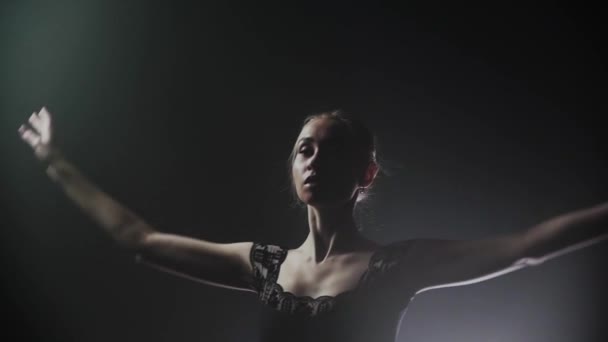 Ung kvinna ballerina i svart klänning utför sin dans på den rökiga scenen — Stockvideo