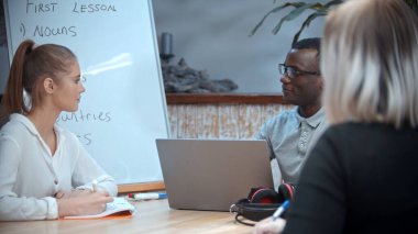 Sınıfta beyaz bir kadın ve siyah bir adam İngilizce dersi alıyor. Öğretmen onları izliyor.