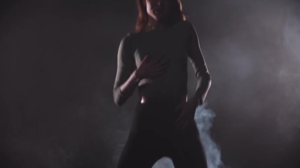 Сексуальная стройная женщина танцует в тёмной дымчатой студии — стоковое видео