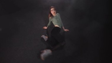 Çekici kadın Kara Duman Stüdyosunda yerde dans ediyor.