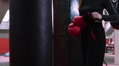 Genç bir kadın boks eldivenlerini giyiyor.