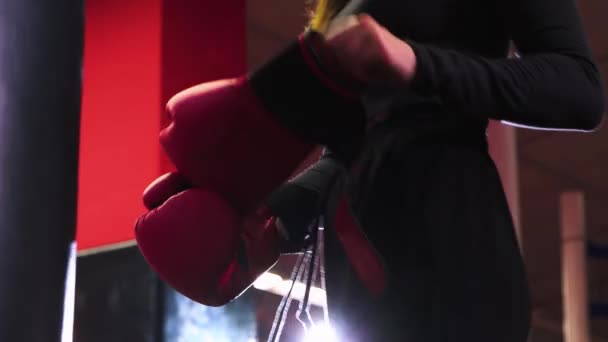 Young woman putting on her boxing gloves in front of the punching bag — Stock Video