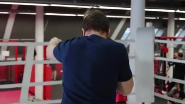 Erkek boks koçu yumruk tekniğini kadın öğrencisine gösteriyor.
