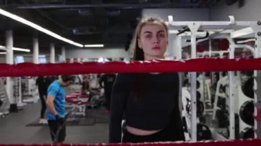 Genç ve güzel bir kadın spor salonundaki boks ringine yürür.