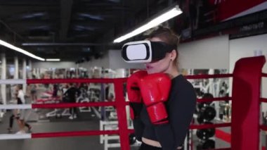 Genç bir kadın yumruklarını sanal gerçeklik gözlüğü takarak eğitiyor. Gölge boksu.