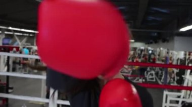 Genç bir kadın ringde boks antrenmanı yapıyor.