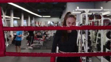 Genç bir kadın spor salonundaki boks ringine yürür.