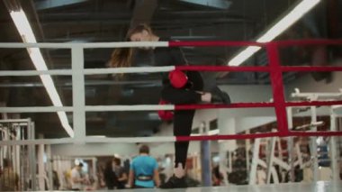 Uzun saçlı genç bir kadın ringe çıkıp boks antrenmanı yapmak üzere.