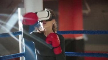 Boks antrenmanı. Boks ringinde VR gözlüğü takan genç bir kadın yumruklarını eğitiyor.