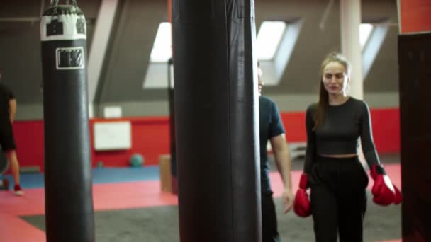 Entrenamiento de boxeo - una mujer atractiva y su entrenador de entrenamiento camina en el gimnasio — Vídeos de Stock